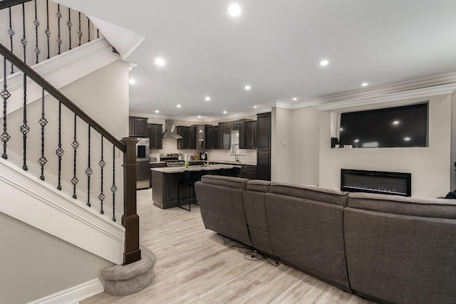 living room with sink, light hardwood / wood-style flooring, and ornamental molding