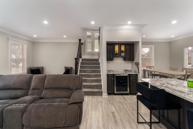 living room featuring ornamental molding, indoor bar, wine cooler, and light hardwood / wood-style flooring