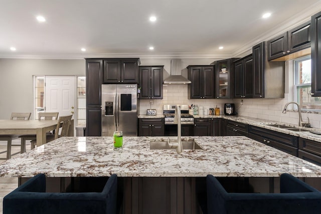 kitchen featuring stainless steel appliances, a spacious island, wall chimney exhaust hood, and a breakfast bar area