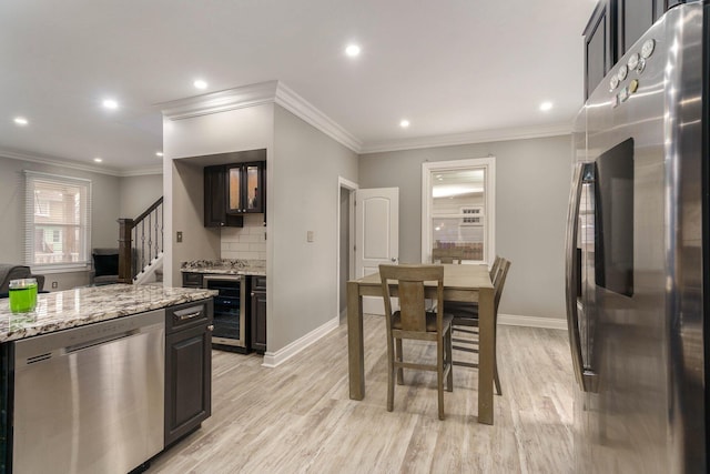 kitchen featuring stainless steel appliances, light stone countertops, ornamental molding, decorative backsplash, and light hardwood / wood-style flooring