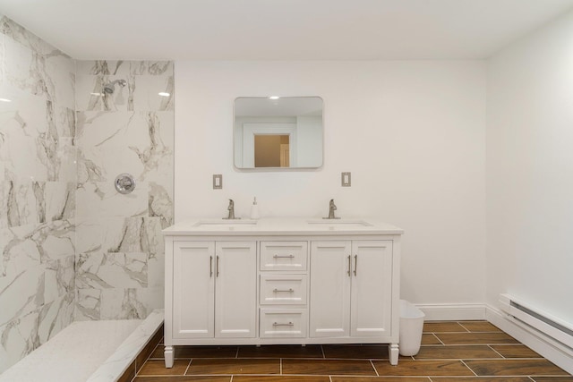 bathroom with baseboard heating, tiled shower, and vanity