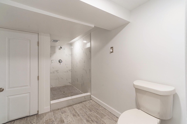 bathroom featuring a tile shower and toilet