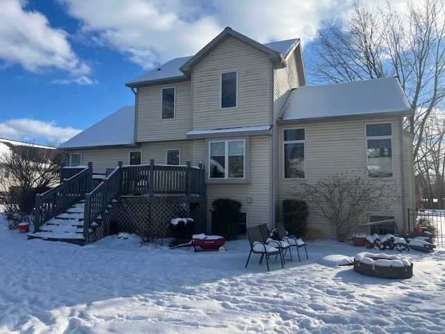 snow covered back of property featuring a wooden deck and an outdoor fire pit