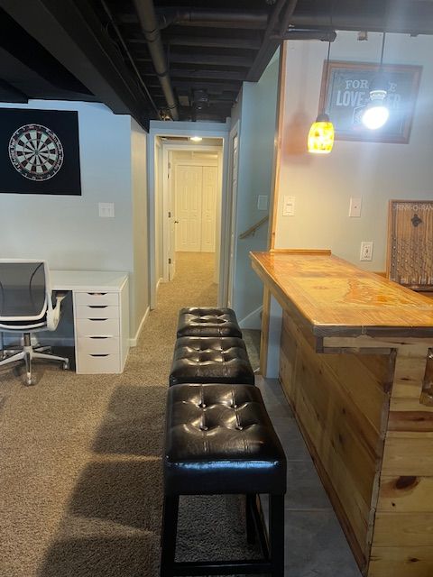 bar featuring decorative light fixtures, butcher block countertops, and dark colored carpet