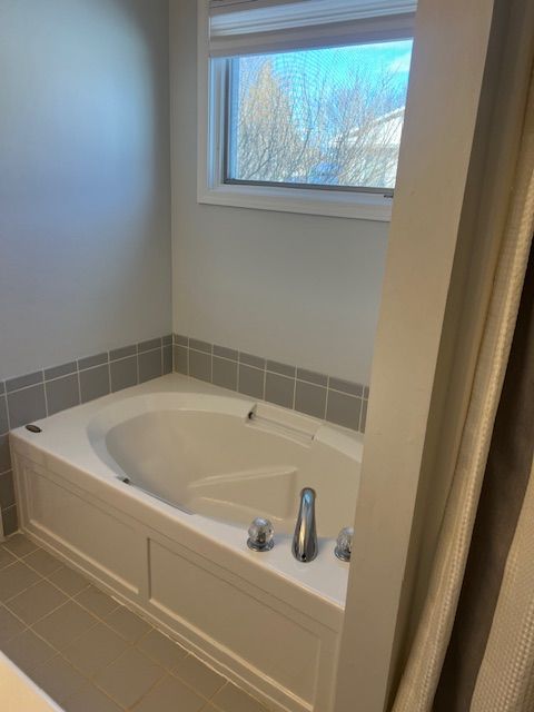 bathroom with a tub to relax in and tile patterned flooring