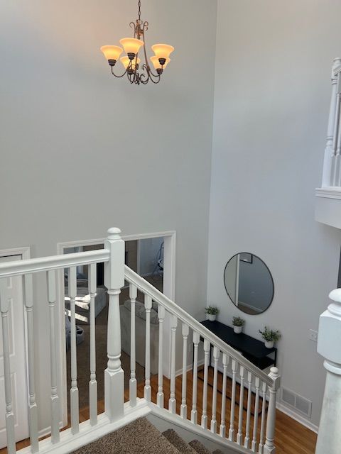 stairway with a notable chandelier and hardwood / wood-style flooring