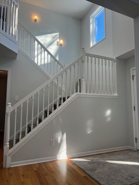 stairs with a high ceiling and wood-type flooring