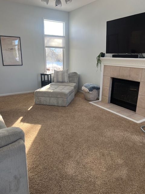 living room featuring ceiling fan, carpet, and a fireplace