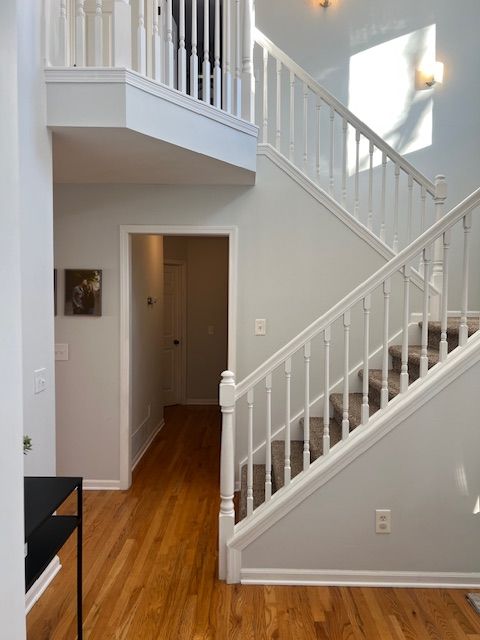 stairway with a towering ceiling and hardwood / wood-style floors