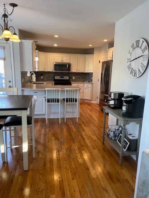 kitchen with stainless steel appliances, sink, white cabinets, decorative light fixtures, and dark wood-type flooring