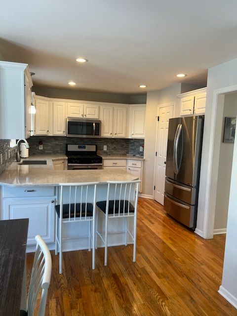 kitchen with sink, stainless steel appliances, white cabinetry, and dark wood-type flooring