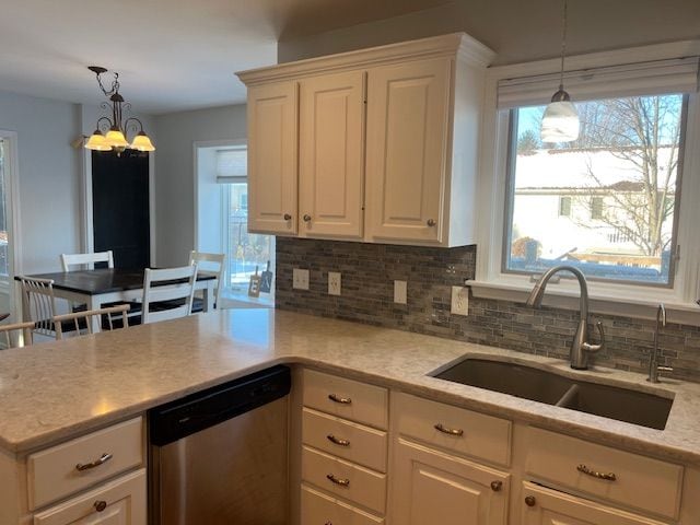 kitchen with sink, a notable chandelier, dishwasher, and pendant lighting