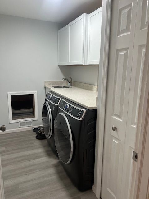 laundry area featuring sink, cabinets, washing machine and dryer, and light wood-type flooring