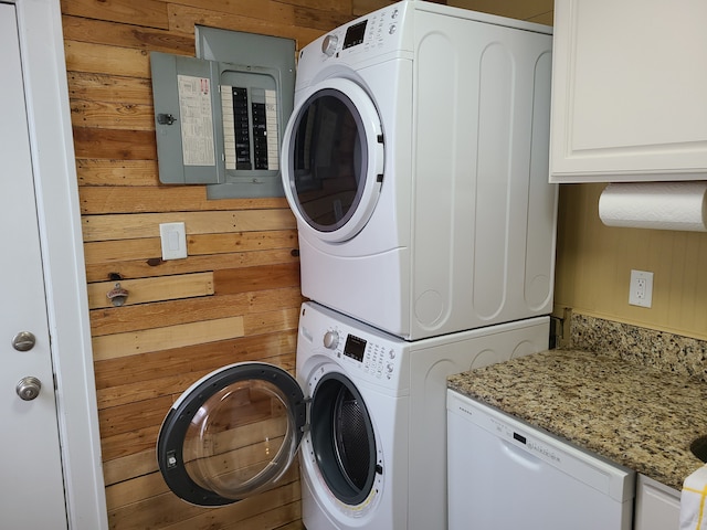 washroom featuring stacked washer and dryer, wood walls, and electric panel