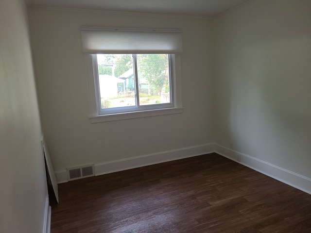 spare room with dark hardwood / wood-style flooring and crown molding