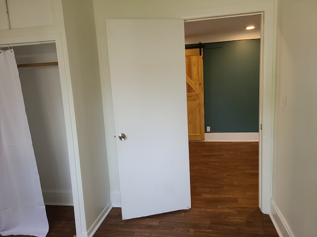 interior space featuring dark wood-type flooring, a closet, and a barn door