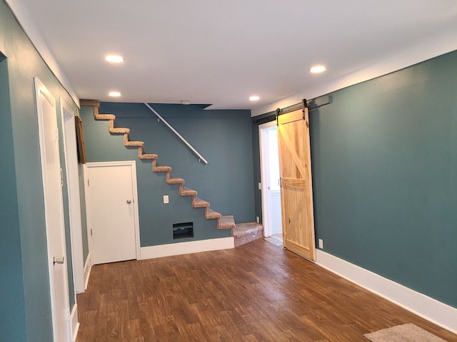 basement with dark wood-type flooring and a barn door