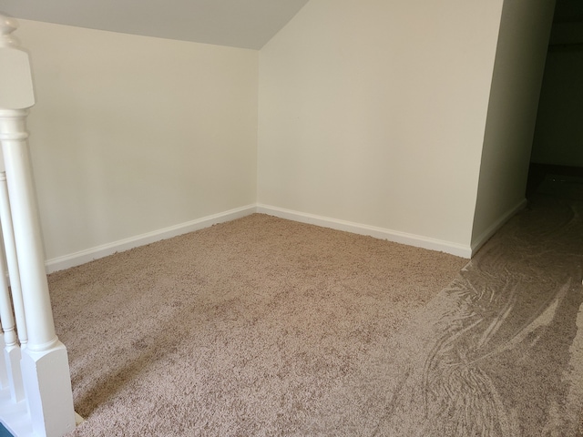 carpeted spare room with vaulted ceiling