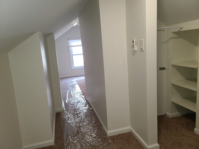 hallway with lofted ceiling and dark carpet