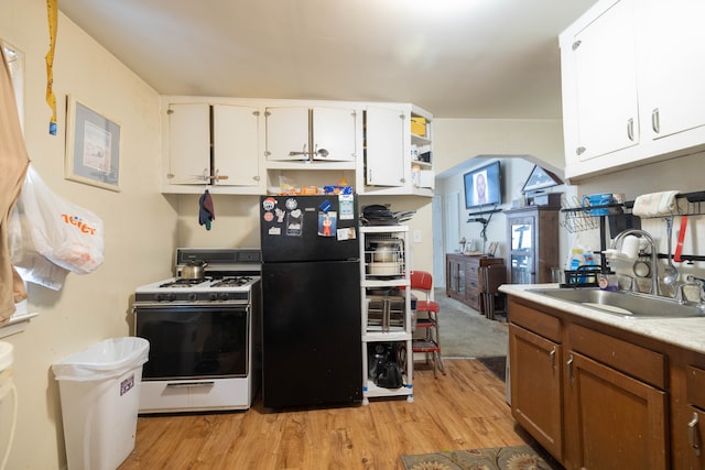 kitchen with sink, white cabinets, white range with gas cooktop, and black fridge