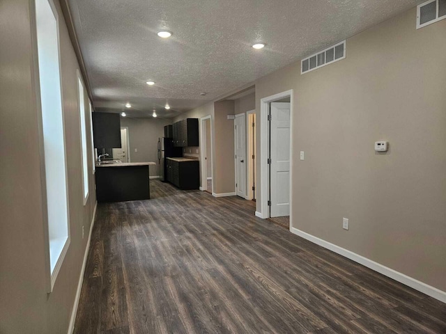 unfurnished living room with a textured ceiling and dark hardwood / wood-style flooring