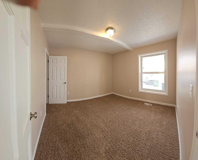 unfurnished room featuring a textured ceiling and carpet