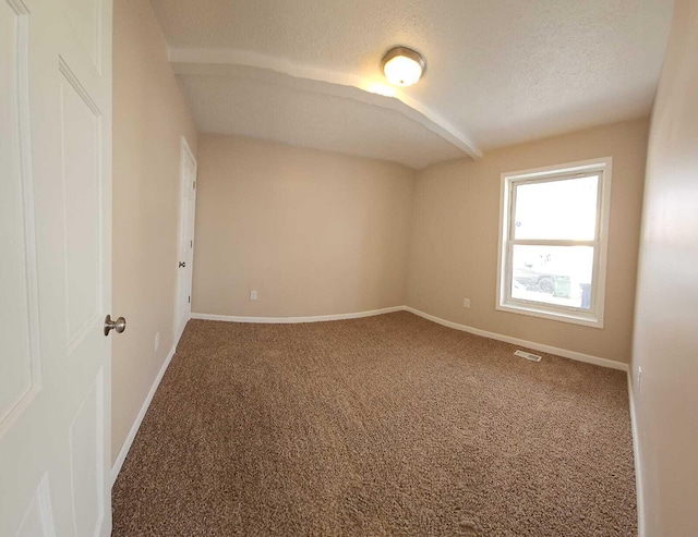 empty room with a textured ceiling and carpet flooring