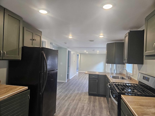 kitchen with black refrigerator, light hardwood / wood-style floors, gas stove, and sink