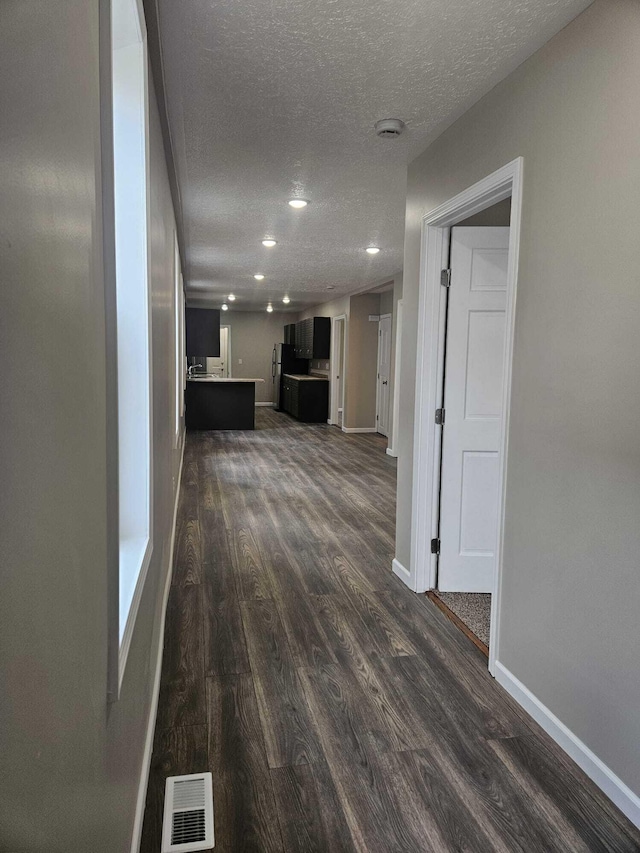 unfurnished living room with a textured ceiling and dark wood-type flooring