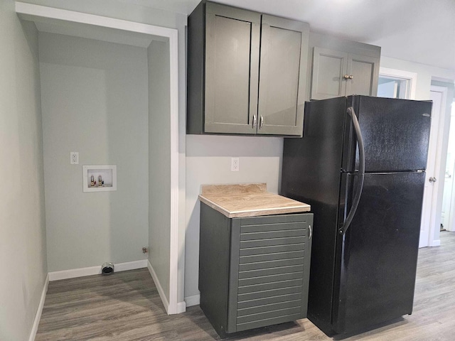 kitchen featuring gray cabinetry, black refrigerator, and hardwood / wood-style floors