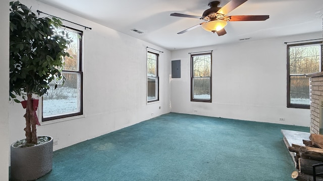 empty room featuring electric panel, ceiling fan, a fireplace, and dark carpet