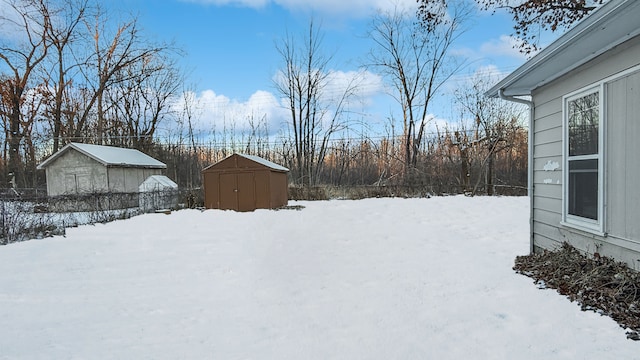 yard layered in snow with a storage shed