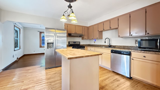 kitchen featuring sink, a center island, butcher block countertops, pendant lighting, and appliances with stainless steel finishes