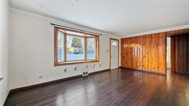 empty room featuring wood walls, ornamental molding, and dark hardwood / wood-style floors