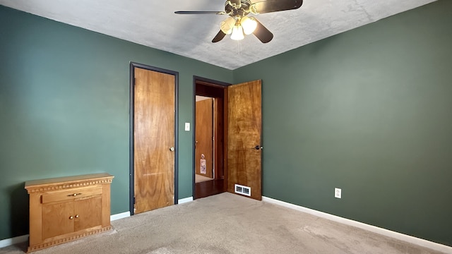 unfurnished bedroom featuring a textured ceiling, carpet floors, and ceiling fan