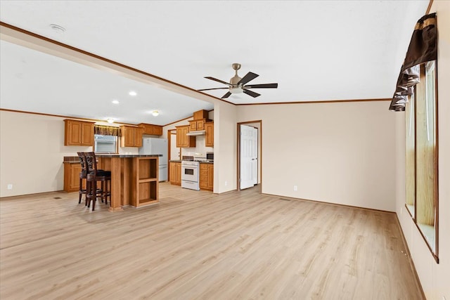 kitchen with a center island, vaulted ceiling, white appliances, a kitchen bar, and ornamental molding