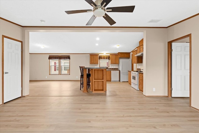 kitchen with white appliances, a center island, light wood-type flooring, ceiling fan, and a kitchen breakfast bar