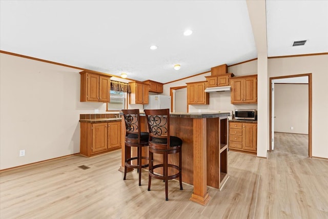 kitchen featuring white fridge, a center island, vaulted ceiling, and crown molding