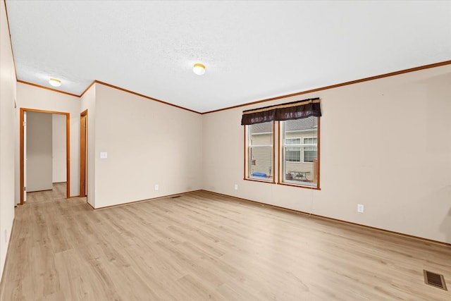 unfurnished room featuring vaulted ceiling, a textured ceiling, light hardwood / wood-style floors, and crown molding