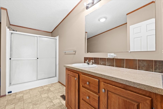 bathroom featuring vanity, ornamental molding, decorative backsplash, a textured ceiling, and an enclosed shower