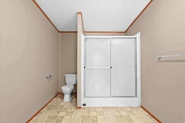 bathroom featuring toilet, a textured ceiling, ornamental molding, and walk in shower