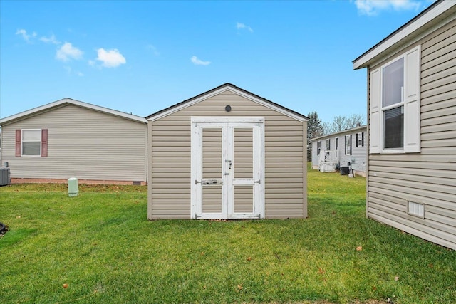 view of outdoor structure featuring central AC unit and a yard