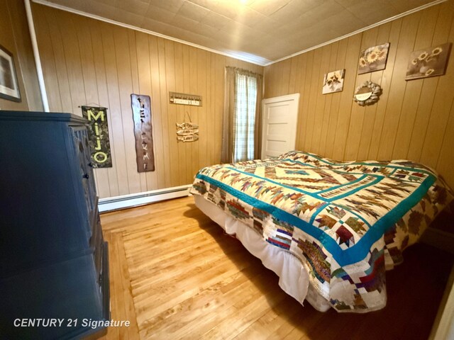 bedroom with hardwood / wood-style flooring, wood walls, a baseboard radiator, and crown molding