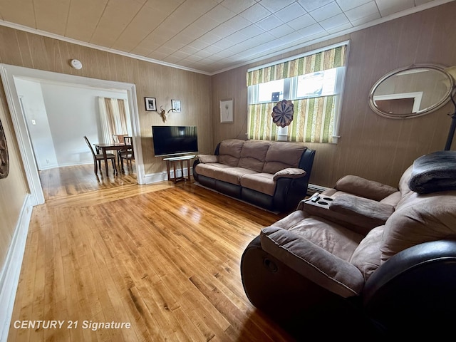 living room featuring ornamental molding, wooden walls, and hardwood / wood-style floors