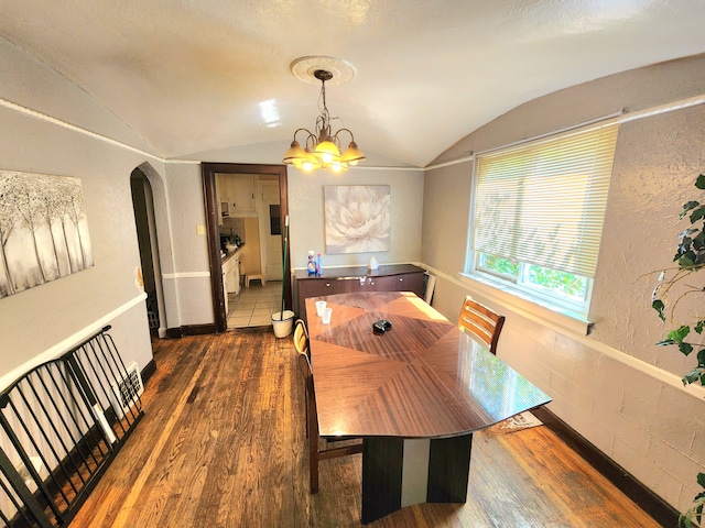 dining room with lofted ceiling, dark hardwood / wood-style flooring, and a chandelier