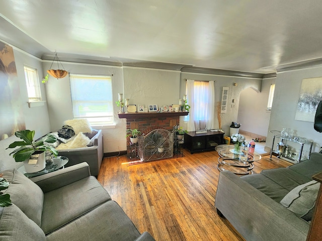 living room featuring plenty of natural light, wood-type flooring, and a brick fireplace