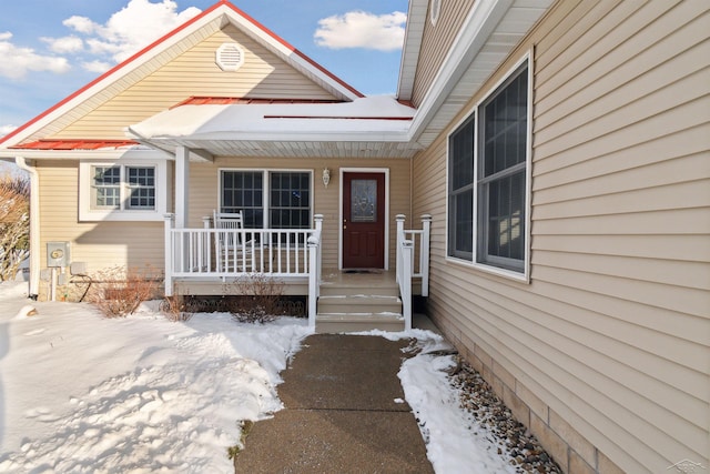 snow covered property entrance featuring covered porch