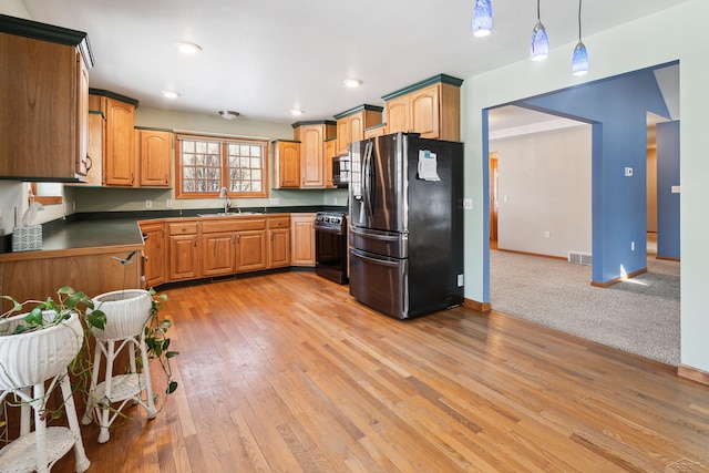 kitchen featuring stainless steel appliances, light carpet, pendant lighting, and sink