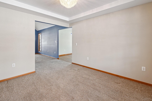 carpeted spare room with a chandelier