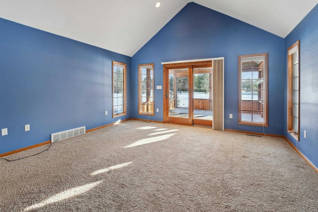 carpeted spare room with high vaulted ceiling